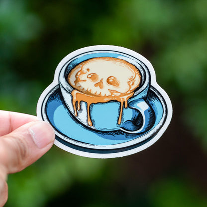 A sticker called Cafe Con Muerte, Evil Latte Art with a skull in the coffee foam
