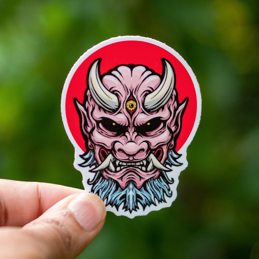 A japanese Oni Demon Yokai sticker, in front of the rising sun flag of Japan.
